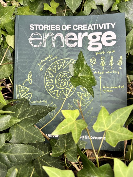 A photograph of the Emerge publication against a background of leaves.